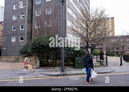 Ein Mann, der am 6. März 2023 in London in einer Plastiktragetasche vor dem Gambier House einkaufte. Gambier House, das 1968 fertiggestellt wurde, ist ein 20-stöckiger, 115-stöckiger flacher Turmblock. Stockfoto