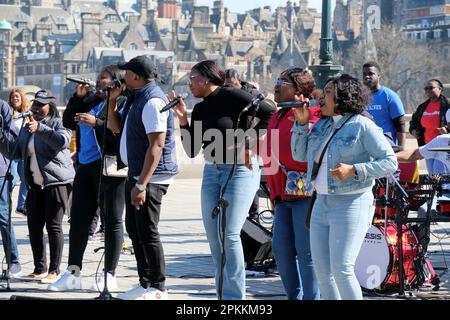 Edinburgh, Schottland, Großbritannien. 8. April 2023 Der RCCG Edinburgh Tabernacle Chor singt mit Gusto und unterhält Urlauber und Besucher am Mound vor dem Hintergrund der Dächer der Altstadt. Kredit: Craig Brown/Alamy Live News Stockfoto