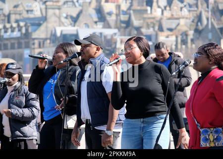 Edinburgh, Schottland, Großbritannien. 8. April 2023 Der RCCG Edinburgh Tabernacle Chor singt mit Gusto und unterhält Urlauber und Besucher am Mound vor dem Hintergrund der Dächer der Altstadt. Kredit: Craig Brown/Alamy Live News Stockfoto