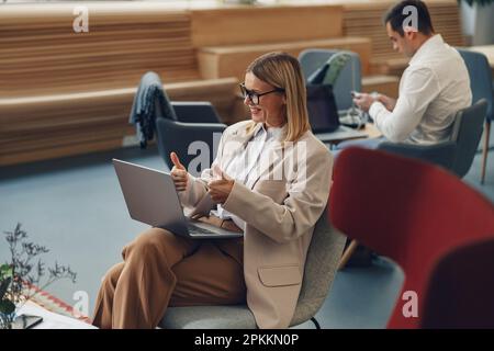 Eine Frau führt ein Videokonferenz, die online mit einem Kollegen spricht, der am Schreibtisch sitzt Stockfoto