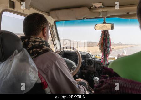 Ein Reiseleiter, der einen Jeep entlang einer Autobahn in der Wüste Ägyptens fährt Stockfoto