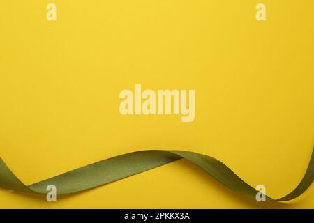 Wunderschönes grünes Band auf gelbem Hintergrund, Draufsicht. Platz für Text Stockfoto
