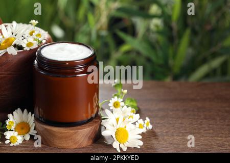 Ein Glas Handcreme und Kamille auf einem Holztisch, Platz für Text Stockfoto