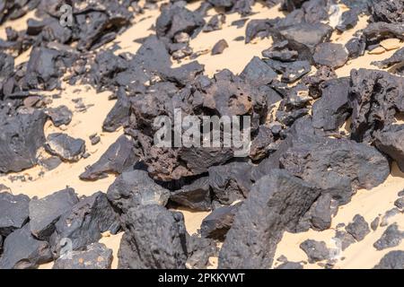 Die freiliegenden schwarzen Basaltfelsen auf einem Hügel in der Schwarzen Wüste in Ägypten Stockfoto