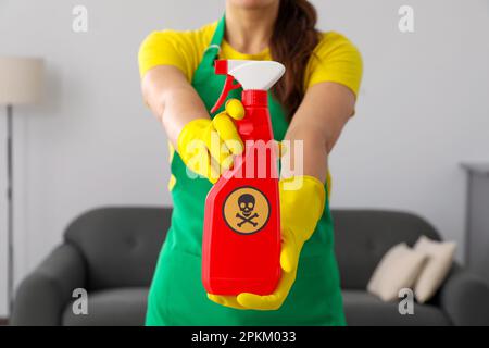 Frau zeigt eine Flasche giftiger Haushaltschemikalien mit Warnschild, Nahaufnahme Stockfoto