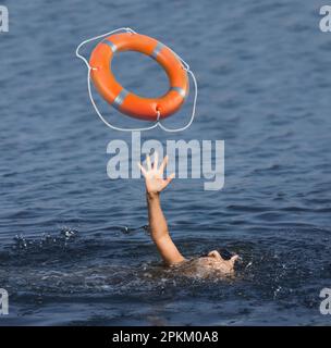 Ertrinkende Frau mit erhobener Hand, Rettungsgürtel im Meer, Nahaufnahme Stockfoto