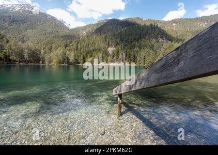 Landschaftsaufnahmen des idyllischen Fernsteinsees in Tirol Österreich mit Holzgeländer, die in das blaue grüne Wasser führen, das teilweise noch schneebedeckt ist Stockfoto