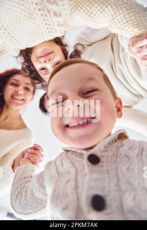 Lächeln und Spaß haben. Ansicht von unten. Glückliche Familie, die nach unten schaut. Stockfoto