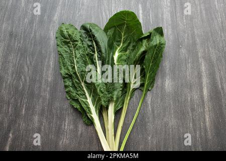 Frisch geerntete große grüne Mangold Blätter bereit zum Zerkleinern und Kochen nahrhafter und gesunder omido auf einem Holztisch Stockfoto