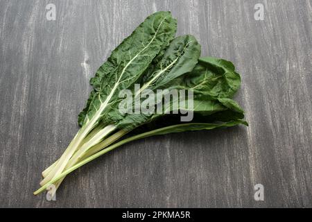 Frisch geerntete große grüne Mangold Blätter bereit zum Zerkleinern und Kochen nahrhafter und gesunder omido auf einem Holztisch Stockfoto