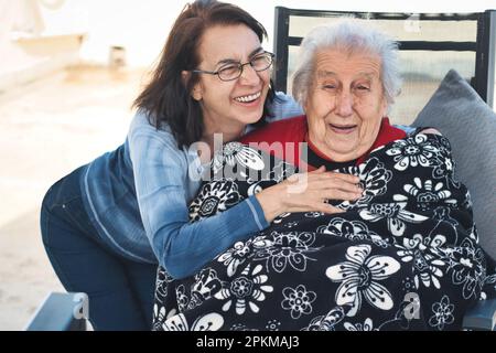 Eine Frau mittleren Alters und eine alte Frau, die Spaß miteinander haben und lachen Stockfoto