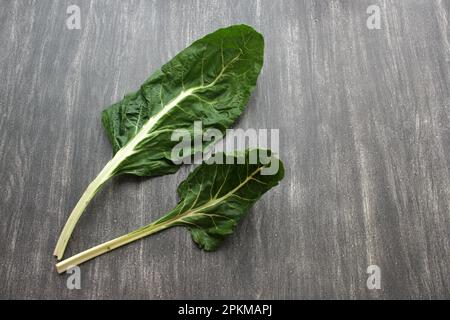 Frisch geerntete große grüne Mangold Blätter bereit zum Zerkleinern und Kochen nahrhafter und gesunder omido auf einem Holztisch Stockfoto