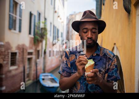 Ein eleganter afrikanischer Junge im Urlaub in Venedig isst ein Eis. Stockfoto