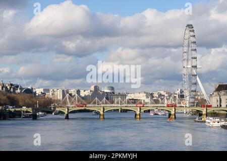 London, Großbritannien - März 17 2023; Rote Busse überqueren die Westminster Bridge auf der Themse mit dem riesigen London Eye Stockfoto