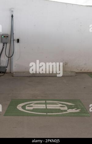 Grünes Schild zum Aufladen von Elektroautos auf dem Boden in der Nähe der EV-Ladestation. Aufgenommen in der Lake Nona Gegend, Florida. Stockfoto