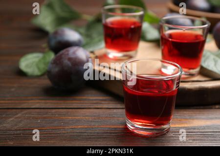 Köstlicher Pflaumenlikör auf einem Holztisch. Hausgemachtes, starkes alkoholisches Getränk Stockfoto