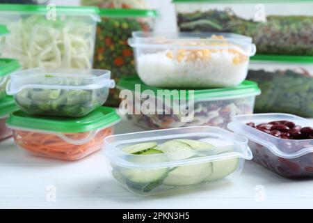 Satz Kunststoffbehälter mit frischen Lebensmitteln auf weißem Holztisch Stockfoto