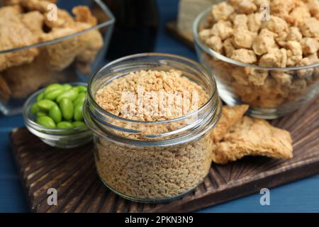 Dehydriertes Sojamleisch und andere organische Produkte auf blauem Tisch, Nahaufnahme Stockfoto