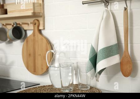 Kanne mit Wasser, Gläser, Handtuch und Utensilien in der Küche Stockfoto
