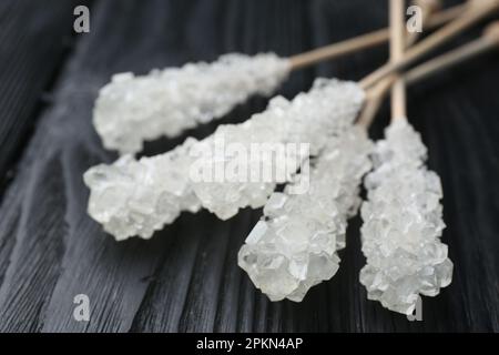 Stäbchen mit Zuckerkristallen auf schwarzem Holztisch, Nahaufnahme. Leckere Rock-Bonbons Stockfoto