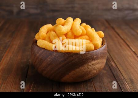 Schüssel mit leckeren käsigen Maispüppchen auf einem Holztisch Stockfoto