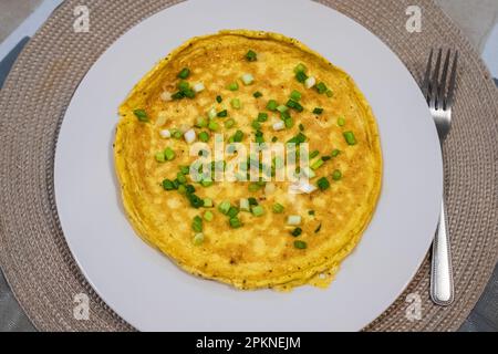 Einfaches Ei-Omelette mit Kräutern auf weißem Teller. Flauschiges Frühstücks-Omelette mit grünen Frühlingszwiebeln. Frühstück mit Spiegeleiern in der Pfanne. Keto ketogene Diät. Stockfoto