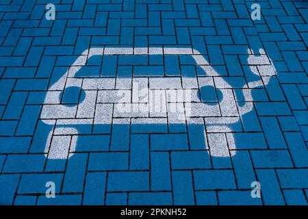 Weißes Elektroauto-Symbol auf blauem Boden in einer Ladestation Stockfoto