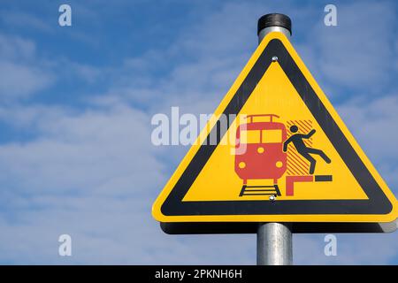 Gelbes dreieckiges Warnschild auf einem Bahnsteig in deutschland, damit man auf vorbeifahrende Züge achten kann, ohne dass es zu Unfällen kommt Stockfoto