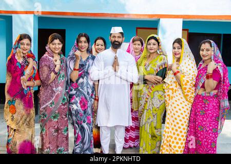 Ein indischer Politiker, der namaste mit einer Gruppe traditioneller Frauen macht. Politikbegriff und Sozialarbeiter. Stockfoto