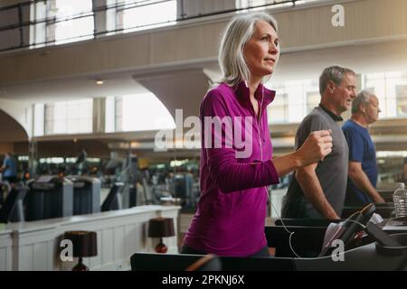 Ihre Fitness-Routine zu verbessern. Eine Gruppe erwachsener Menschen, die auf Laufbändern im Fitnessstudio trainieren. Stockfoto