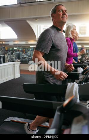 Halte deinen Kopf oben und dein Herz stark. Eine Gruppe erwachsener Menschen, die auf Laufbändern im Fitnessstudio trainieren. Stockfoto