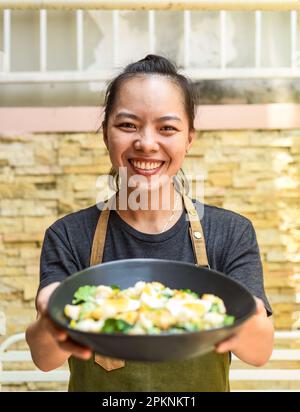 Vietnamesische Kellnerin, die Caesar-Salat in der Hand hat Stockfoto