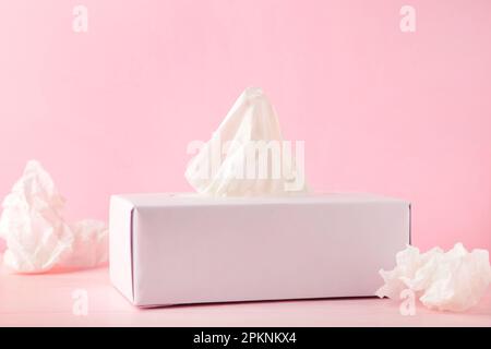 Box mit Papiertüchern und gebrauchten zerbrochenen Servietten auf pinkfarbenem Hintergrund. Draufsicht Stockfoto