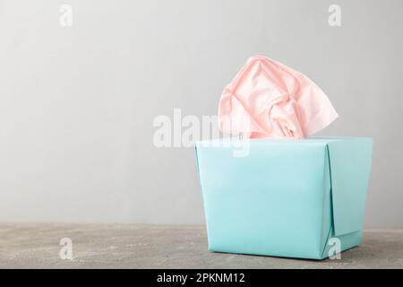 Blaue Box mit Papiertüchern auf grauem Hintergrund mit Kopierbereich. Draufsicht Stockfoto
