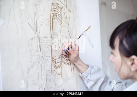 Künstlerin malt mit Pinsel und schwarzer Farbe. Grafisches Malen. Moderne Kunst erschaffen Stockfoto