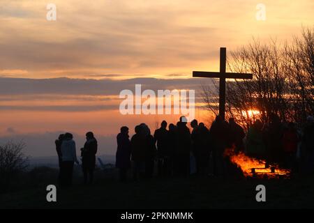 Silhouetten von Menschen versammelten sich am Osterkreuz bei Sonnenaufgang, nachdem sie die Morgenkommunion am Ostertag, dem 9. April 2023, gefeiert hatten. Stockfoto