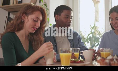 Glückliche Freunde, die zu Hause zusammen frühstücken Stockfoto