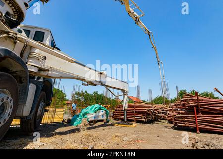 Der verlängerte Seitenausleger bietet Halt und Stabilität für den Lkw mit Pumpe zum Gießen von Beton, das gedehnte Hydrauliksystem, am Bau Stockfoto