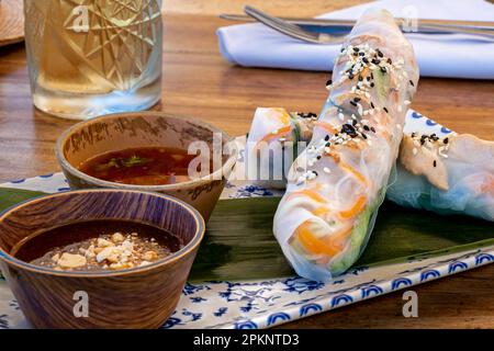 Bereit Gỏi Cuốn vietnamesischen Sommerrollen, frische Zutaten in Reispapier verpackt und serviert mit Saucen, für eine erfrischende und gesunde Ernährung. Stockfoto