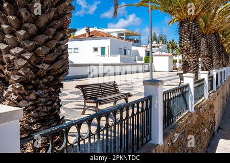 An einem sonnigen Tag im Mai führt die Balustrade entlang der ruhigen Av. Die Promenade DOS Pescadores im charmanten Algarve-Dorf Luz bietet einen Blick auf Praia da Luz. Stockfoto