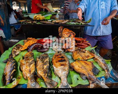 Iquitos, Peru - 2018. März: Gebackener Fisch und andere lokale Köstlichkeiten auf dem Belavista-Markt am Amazonasufer. Amazon. Südamerika Stockfoto