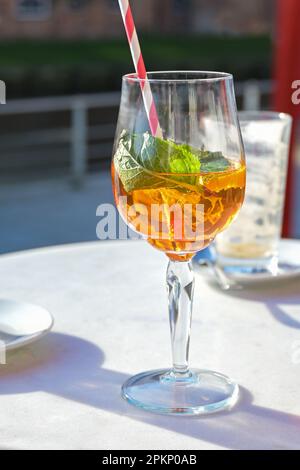 Aperol Spritz Getränk mit Eis und Minzblättern in einem Glas auf einem Tisch in einem Straßencafé in der Stadt an einem sonnigen Tag, Kopierbereich, ausgewählter Fokus, enge Tiefe von f Stockfoto