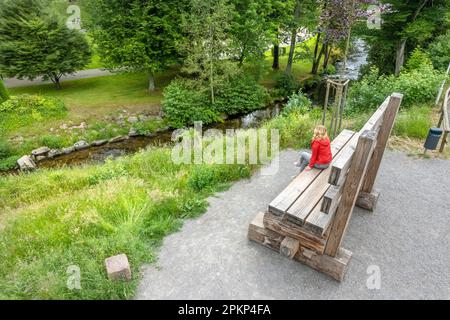 Luftaufnahme einer Frau auf einer übergroßen Bank in Kurgärten, Bad Wildbad, Schwarzwald, Deutschland, Europa Stockfoto