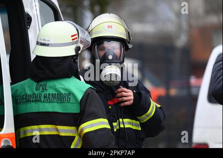 Hamburg, Deutschland. 09. April 2023. Die durch Gasmasken geschützten Feuerwehrleute stehen während eines Großeinsatzes in zwei brennenden Lagerhäusern im Bezirk Rothenburgsort. Die Feuerwehr warnt vor Gefahren durch Rauchgase und chemische Bestandteile in der Luft, die sie einatmen. Kredit: Jonas Walzberg/dpa/Alamy Live News Stockfoto