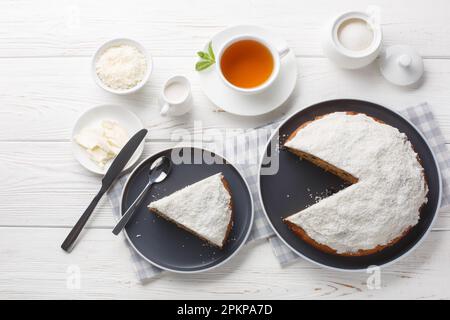 Klassisches Bostoner Brötchen, beliebt in Australien und Neuseeland, serviert mit Tee aus der Nähe auf einem Holztisch. Horizontale Draufsicht von oben Stockfoto