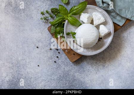 Hausgemachter Molke-Ricotta-Käse oder Hüttenkäse mit Basilikum zum Essen. Vegetarische gesunde Ernährung, Gärung Lebensmittelkonzept. Blick von oben. Kopieren Sie Spac Stockfoto