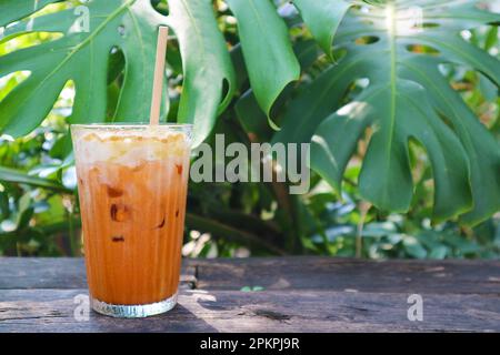 Ein Glas köstlicher thailändischer Eistee auf einem Gartentisch Stockfoto