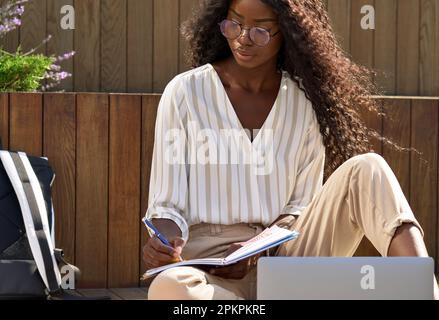 Afrikanische Universitätsstudentin, die mit dem Notebook Notizen zum e-learning macht. Stockfoto