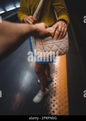 Der Dieb stiehlt einer Frau in der U-Bahn eine Tasche. Stockfoto