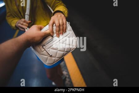 Der Dieb stiehlt einer Frau in der U-Bahn eine Tasche. Stockfoto